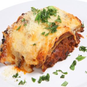 Baked lasagne verdi garnished with fresh basil leaves on a white plate